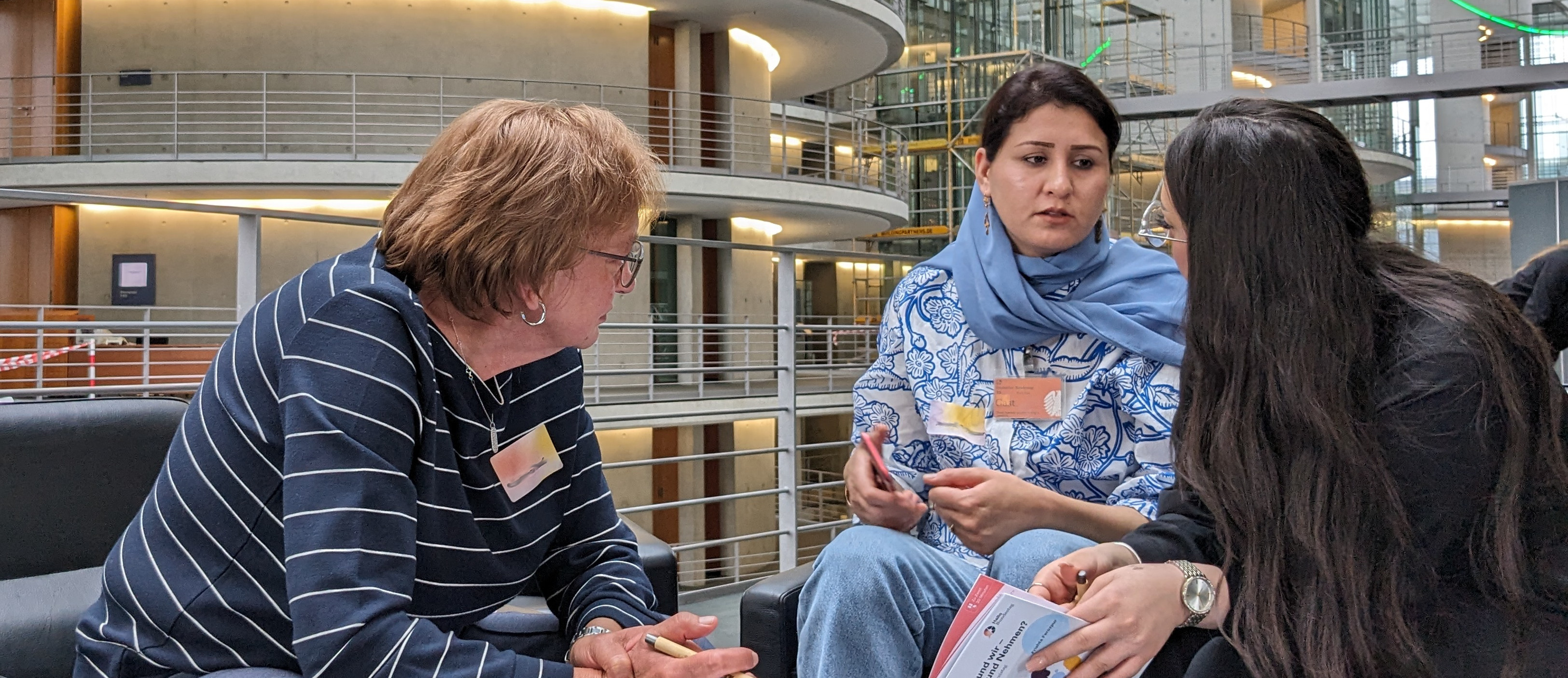 Drei Personen sitzen um einen Tisch im Gespräch im Bundestagsgebäude.